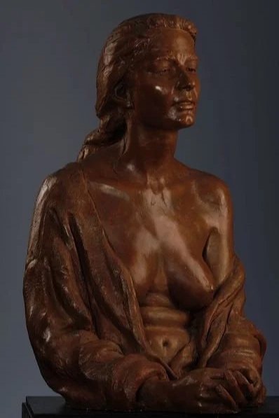 Bronze sculpture of a woman with her hair pulled back, wearing an open shirt and gazing forward.