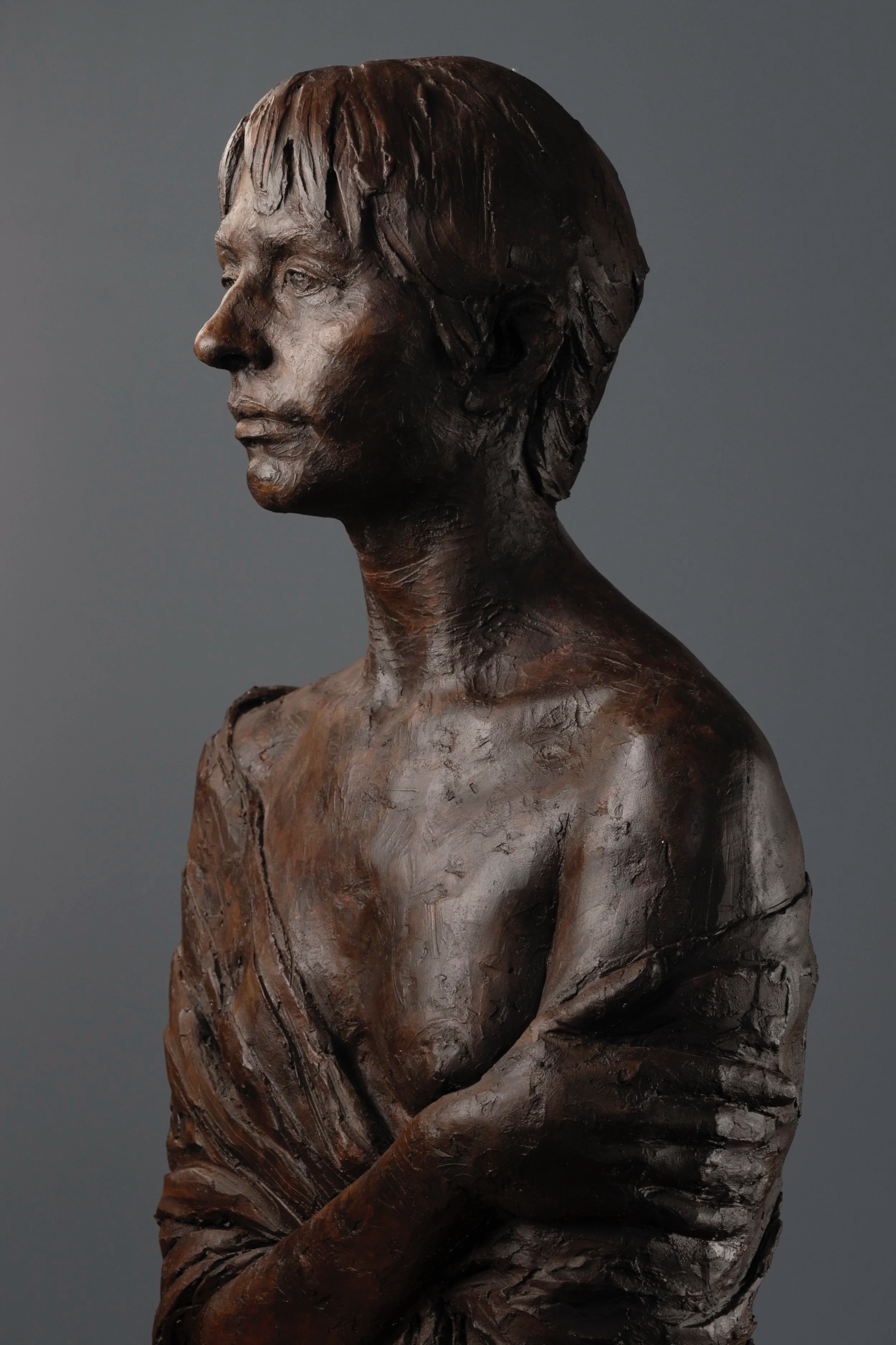 Bronze bust sculpture of a woman's profile with short hair and crossed arms.