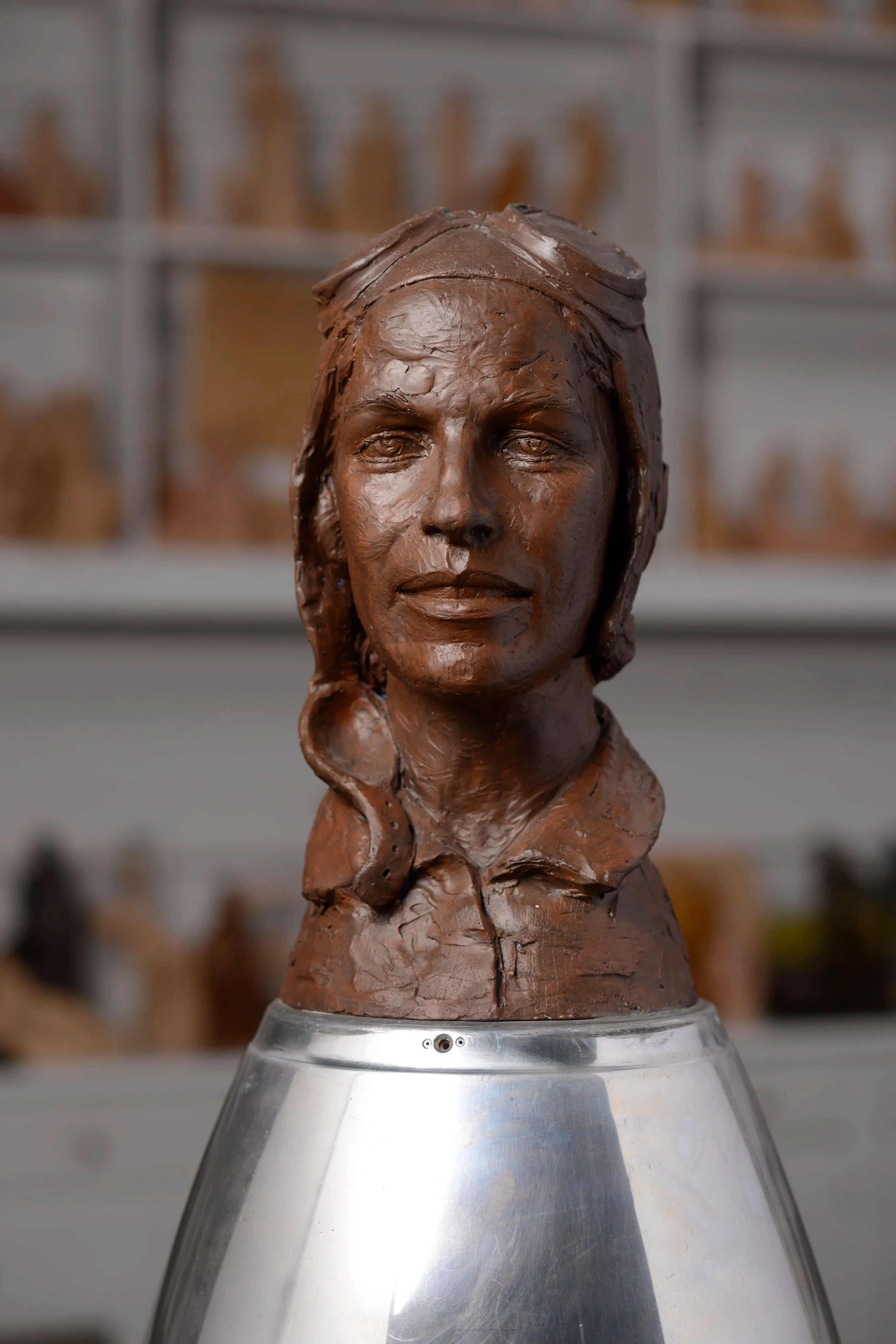 Bronze bust of a woman's face and upper shoulders on a metallic display stand. Amelia Earnheart