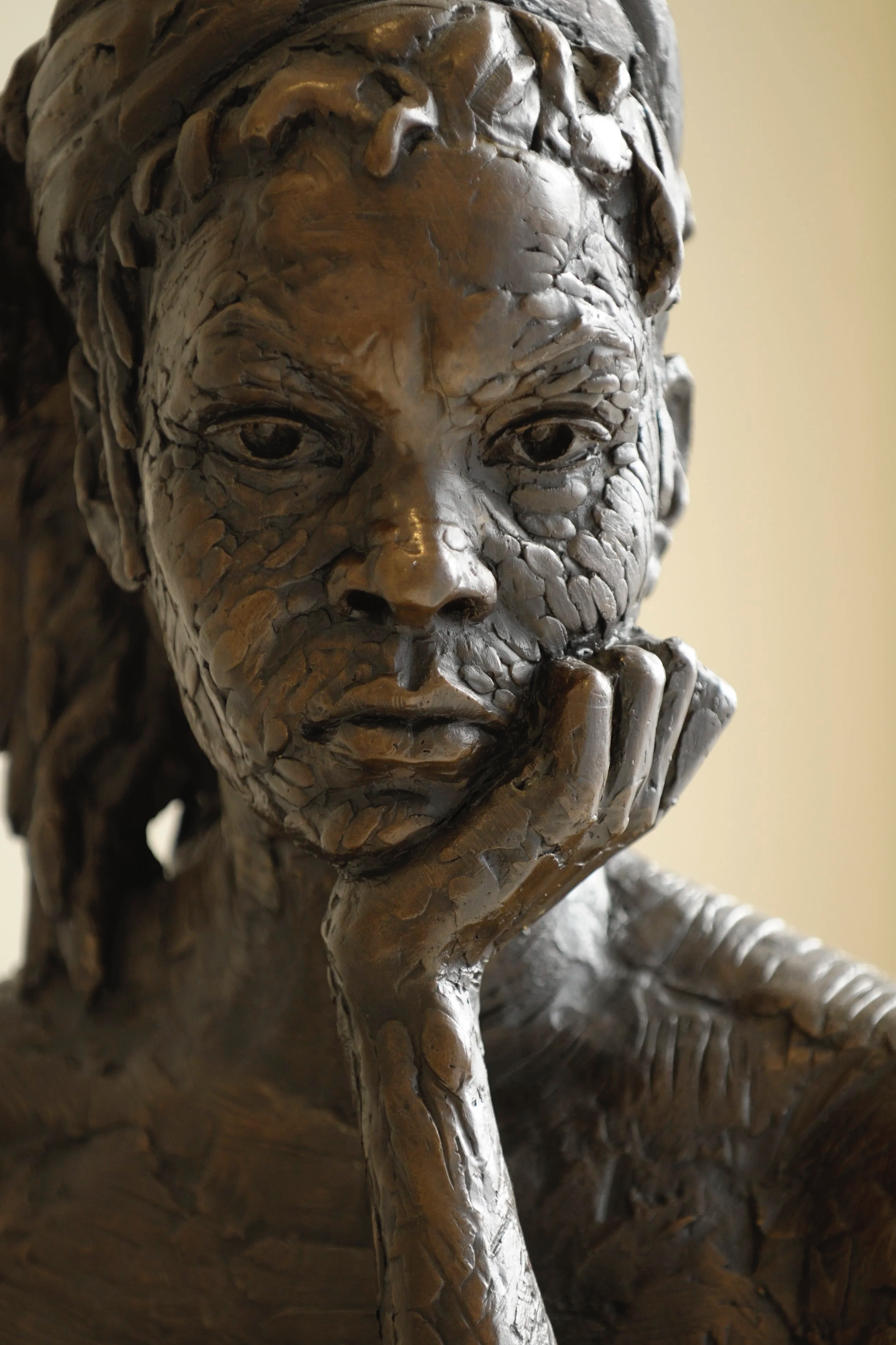 Close-up of a bronze sculpture of a thoughtful person with their hand on their chin.