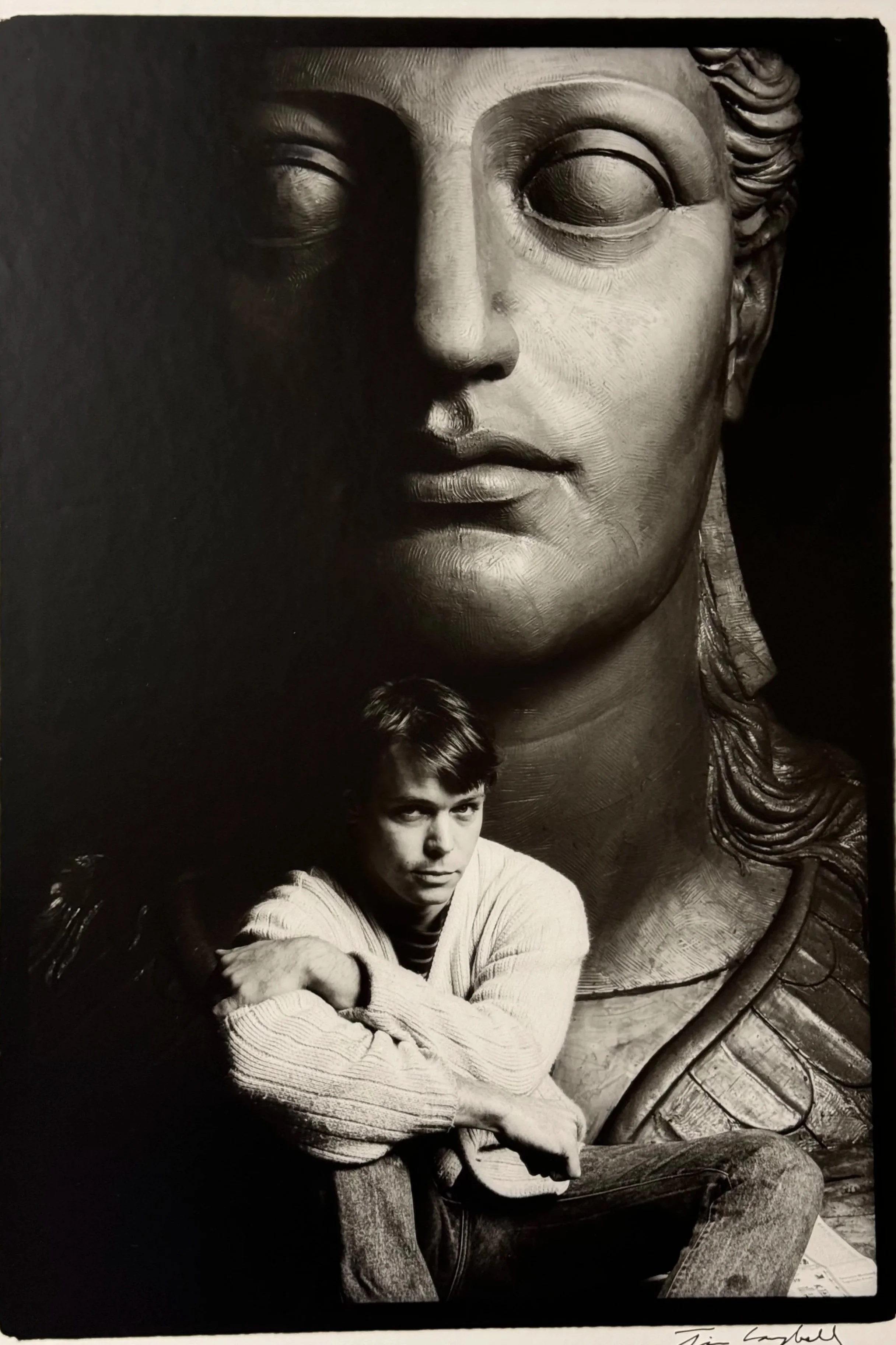 A large black and white mural photo of Athena made in clay with sculptor Alan LeQuire sitting in front of the clay sculpture. 