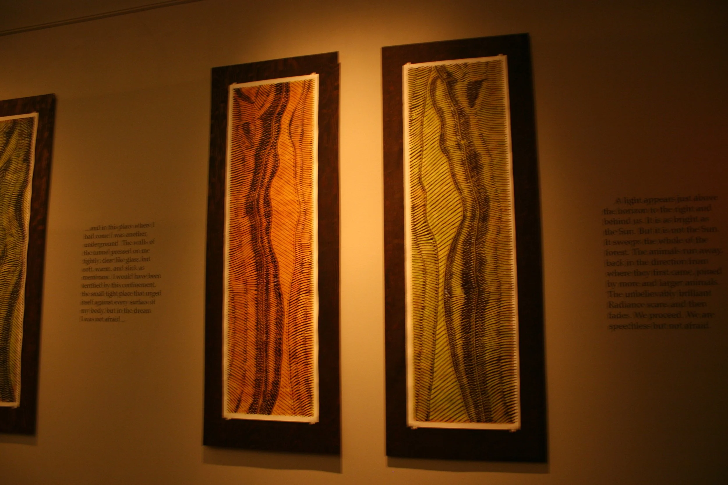 Three framed abstract artworks featuring wavy, striped patterns in warm colors, displayed on a beige wall with accompanying text. Dream Forest Wood Block Prints.