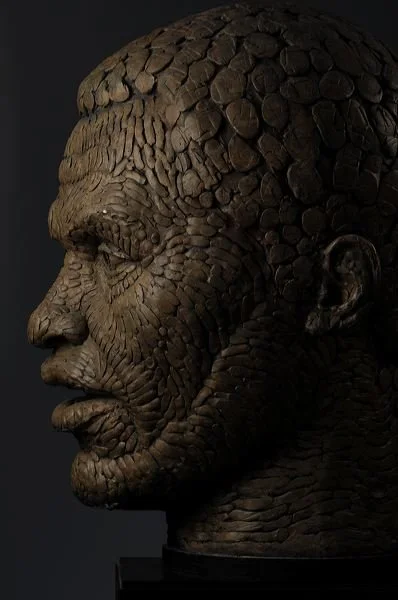 A detailed sculpture of a man's face made from small, round stones arranged to resemble skin texture.