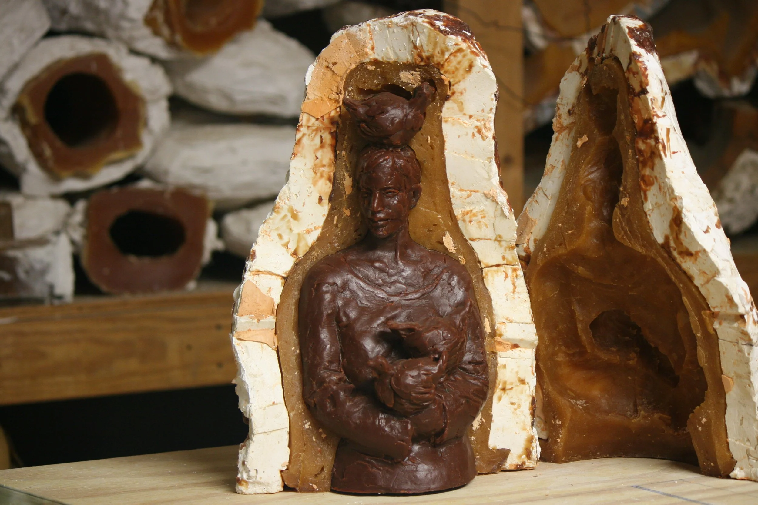 Sculpture of a woman with a chicken on her head, cast in wax and in a mold.