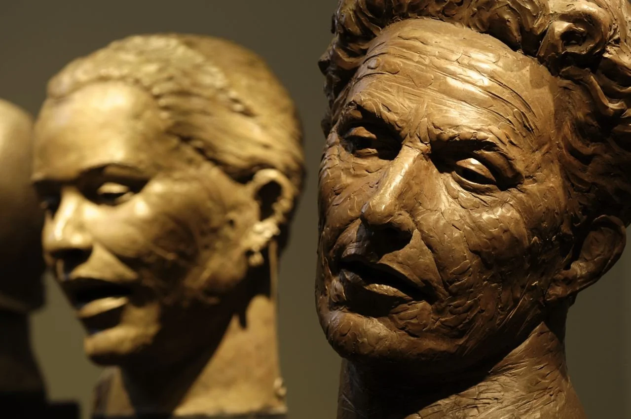 Two plaster sculptures of African American women and man, one with closely styled hair and the other with a natural hairstyle, displayed in a museum.  Cultural Heroes
