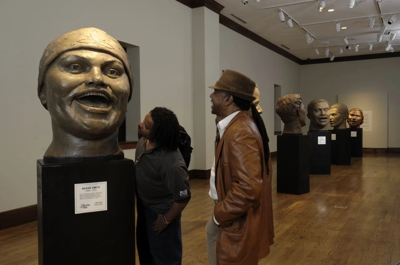 People viewing sculptures of African American leaders and figures in an art museum or gallery.  Cultural Heroes