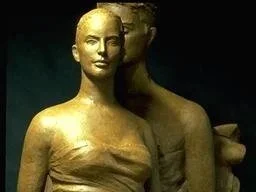 Golden statue of a woman with a second statue of a headless woman behind her.