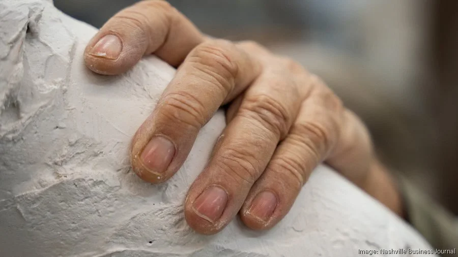 Close-up of a person's hand gripping a textured white surface or object.