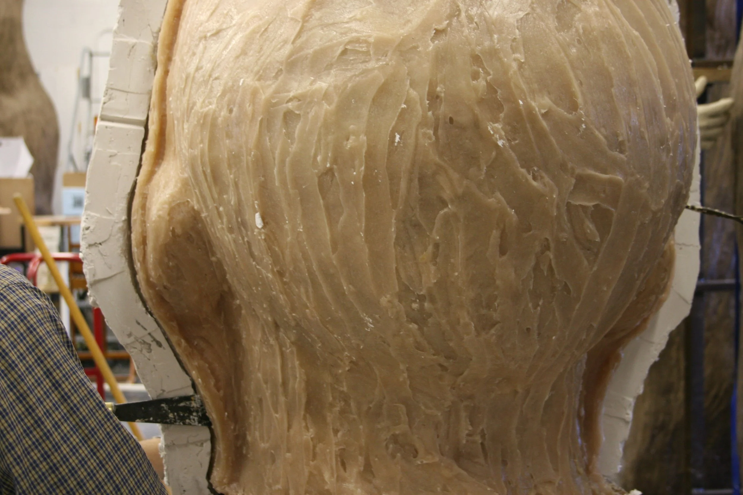 A rubber and plaster mold partially cut, on a worktable in a workshop.