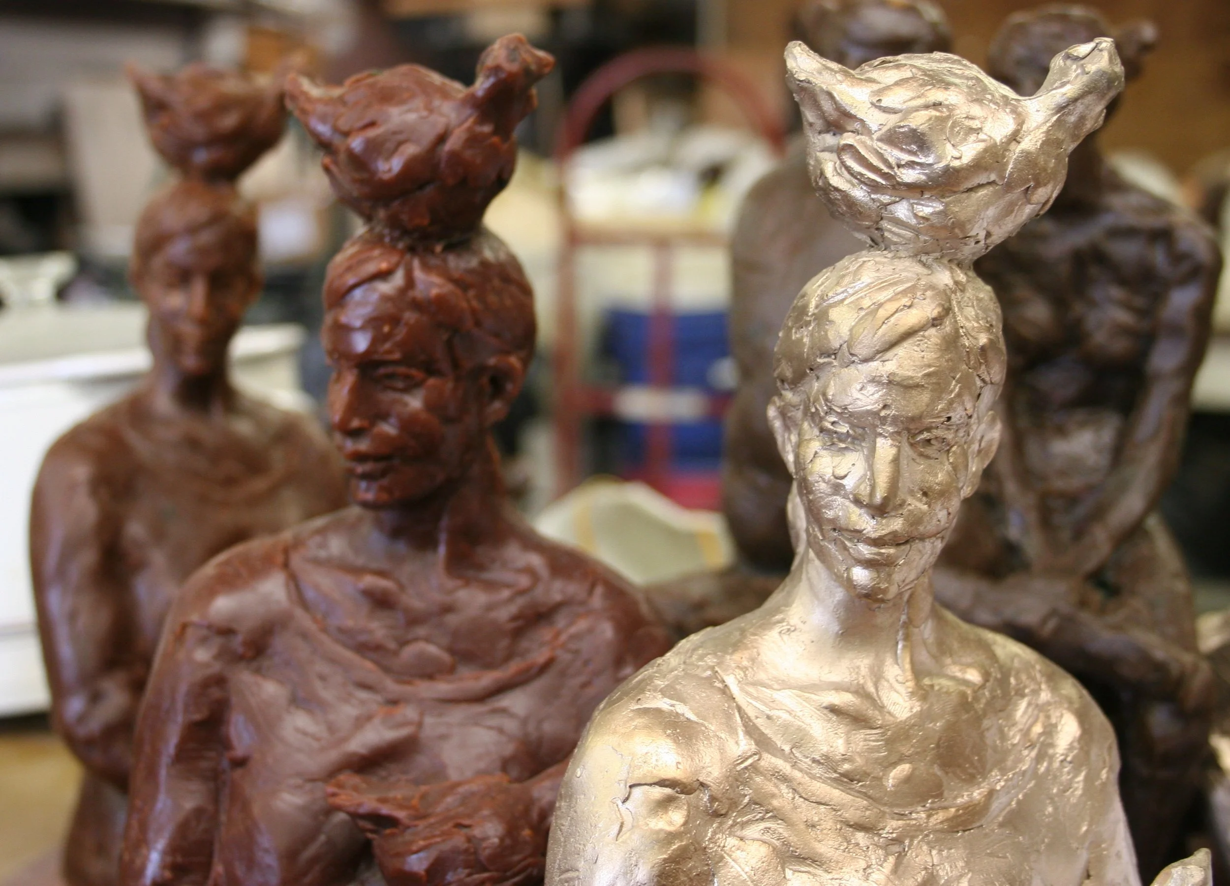 Bronze and wax sculptures of a woman with chickens.