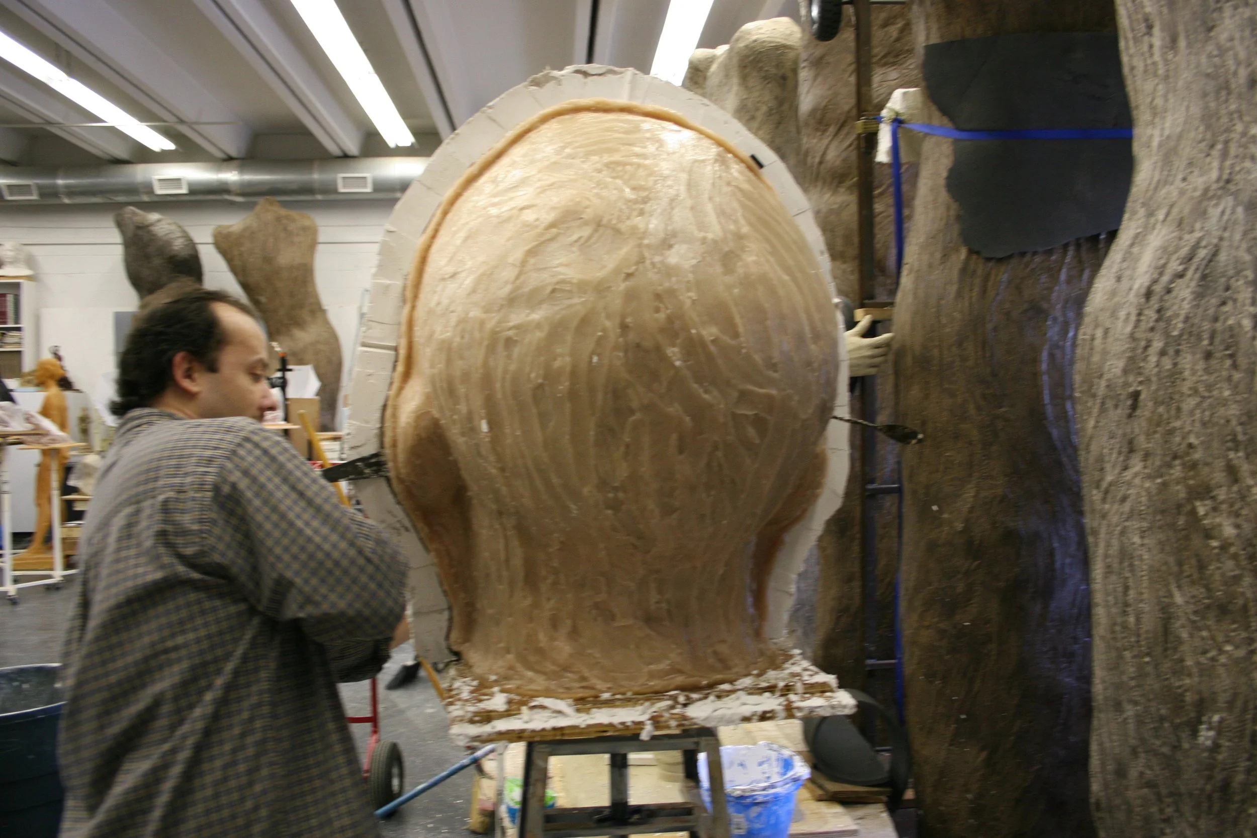 A person working on a rubber mold of a sculpture in a workshop.
