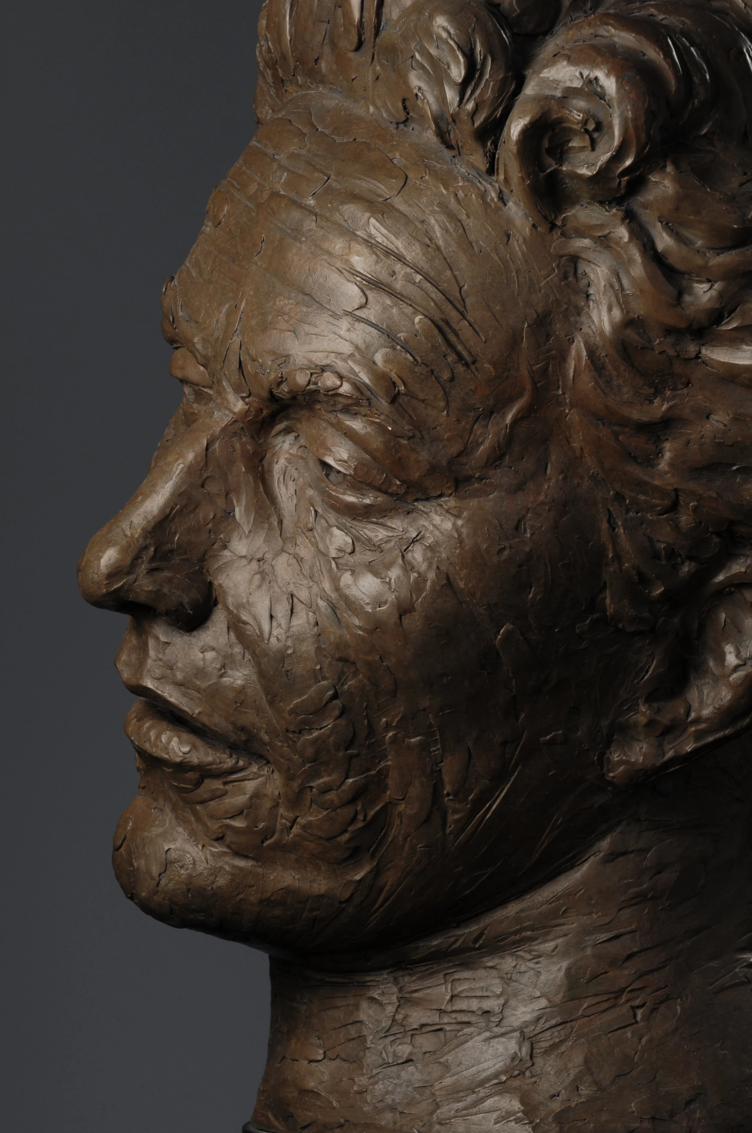 Close-up photo of a wooden sculpture of a man's profile with detailed features and textured surface.