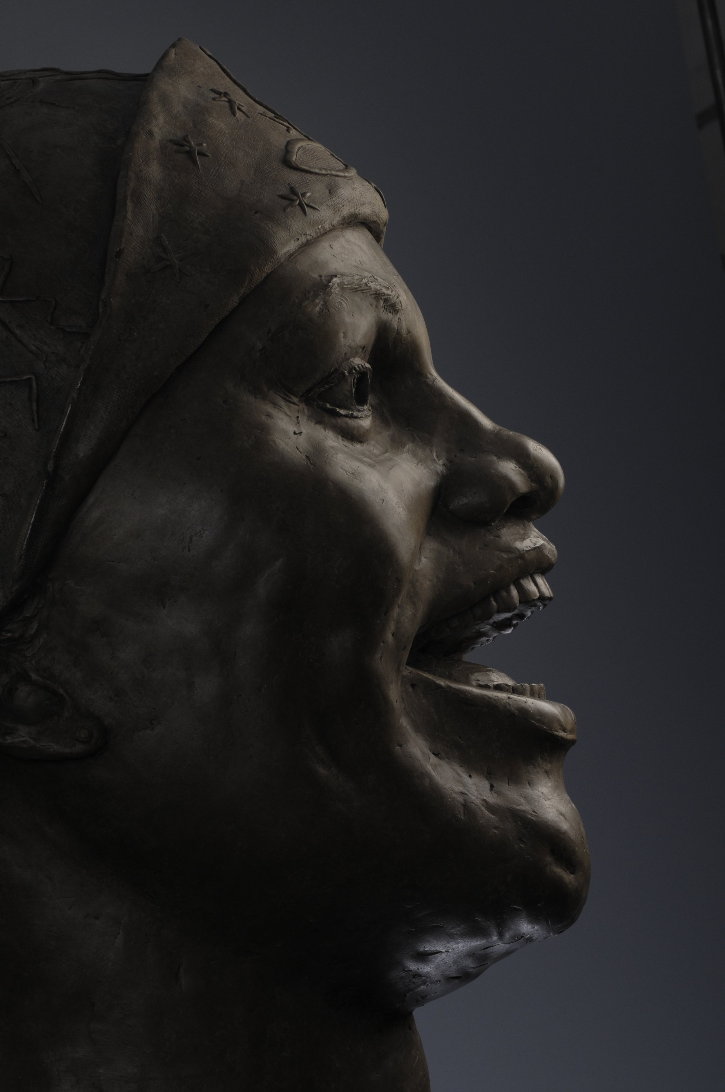 Close-up of a bronze statue featuring a side profile of a person's face, including eyes, nose, mouth, and chin, with a dark background. Cultural Heroes Bessie Smith