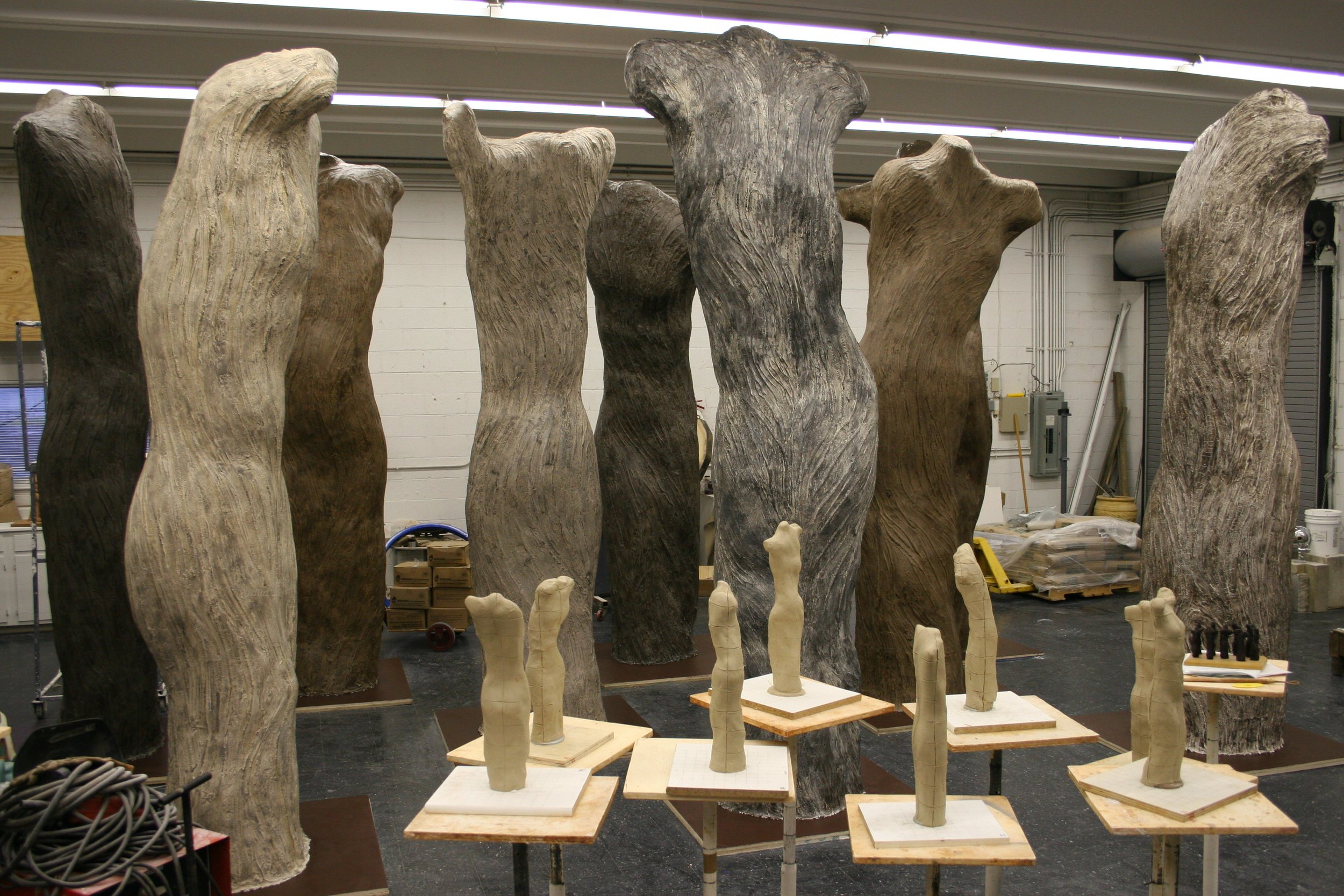 Wooden sculptures of human body parts, such as legs and torsos, in an artist's workshop.