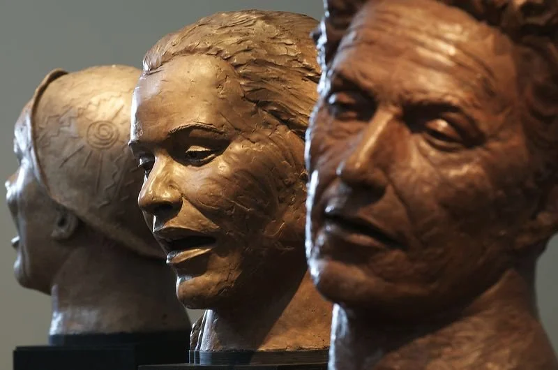 Three bronze busts of diverse individuals displayed in a row, each with distinct facial features and hairstyles.  Cultural Heroes