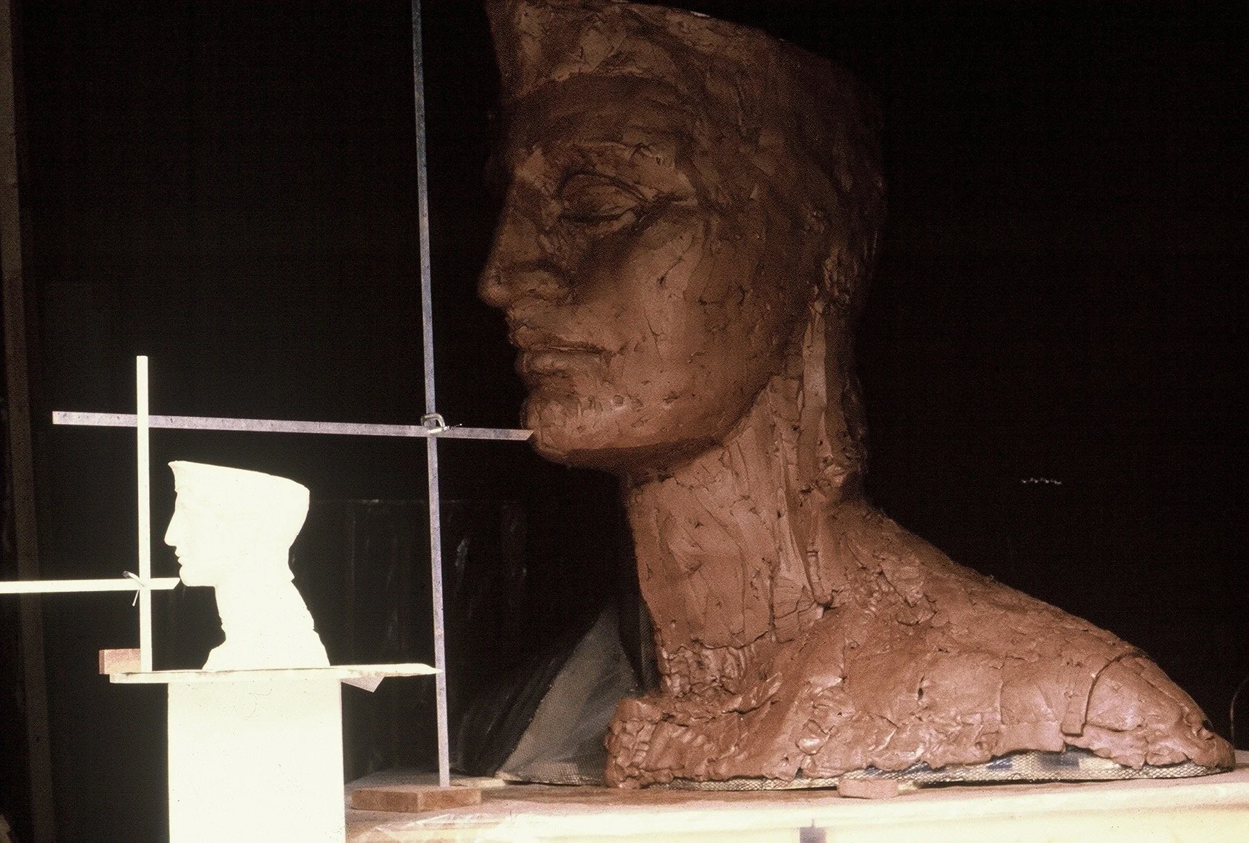 A large sculpture of a woman's head and upper body made from clay, with a textured surface. The sculpture is displayed indoors against a dark background. Athena Parthenos in Parthenon Museum Nashville.
