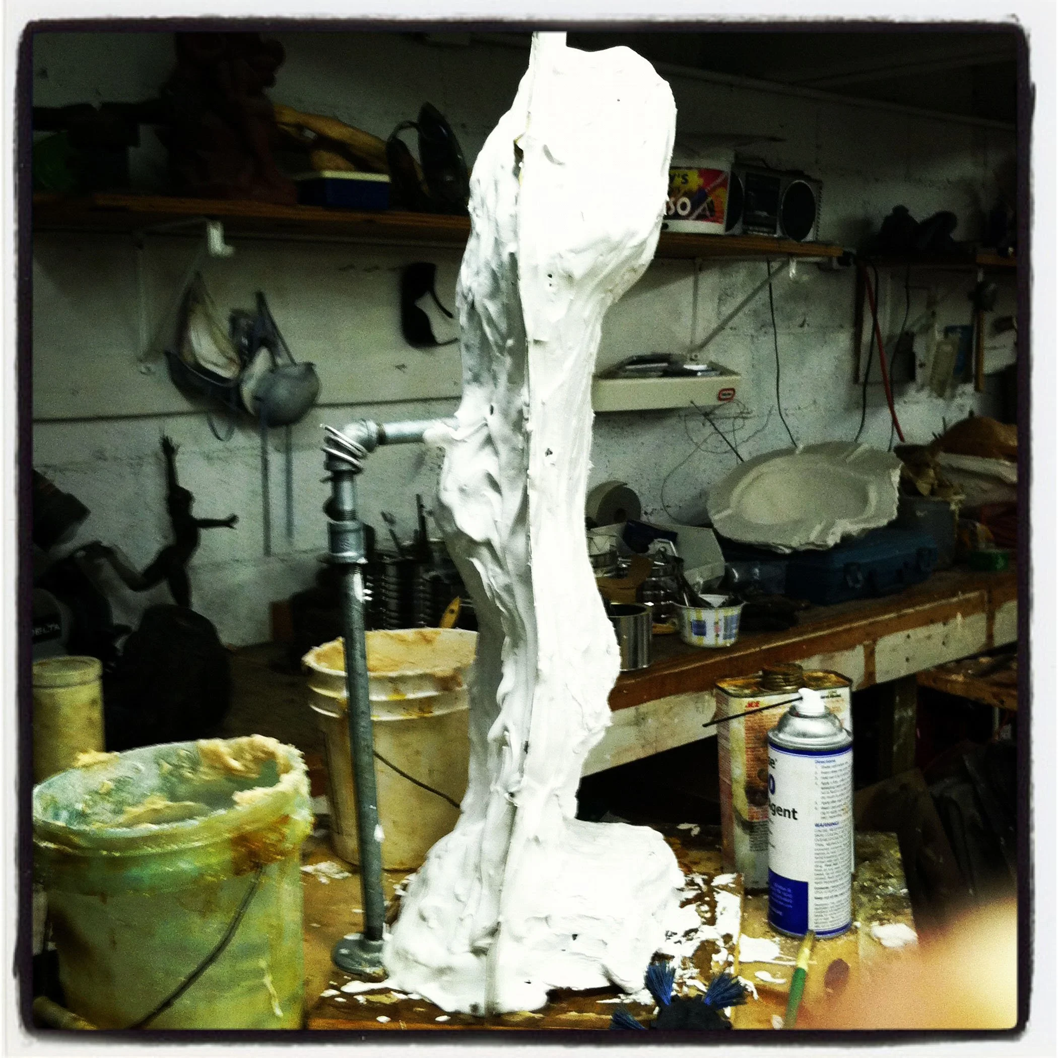 A cluttered storage area with tools, paint cans, and miscellaneous sculpture items. Sculpture of mold