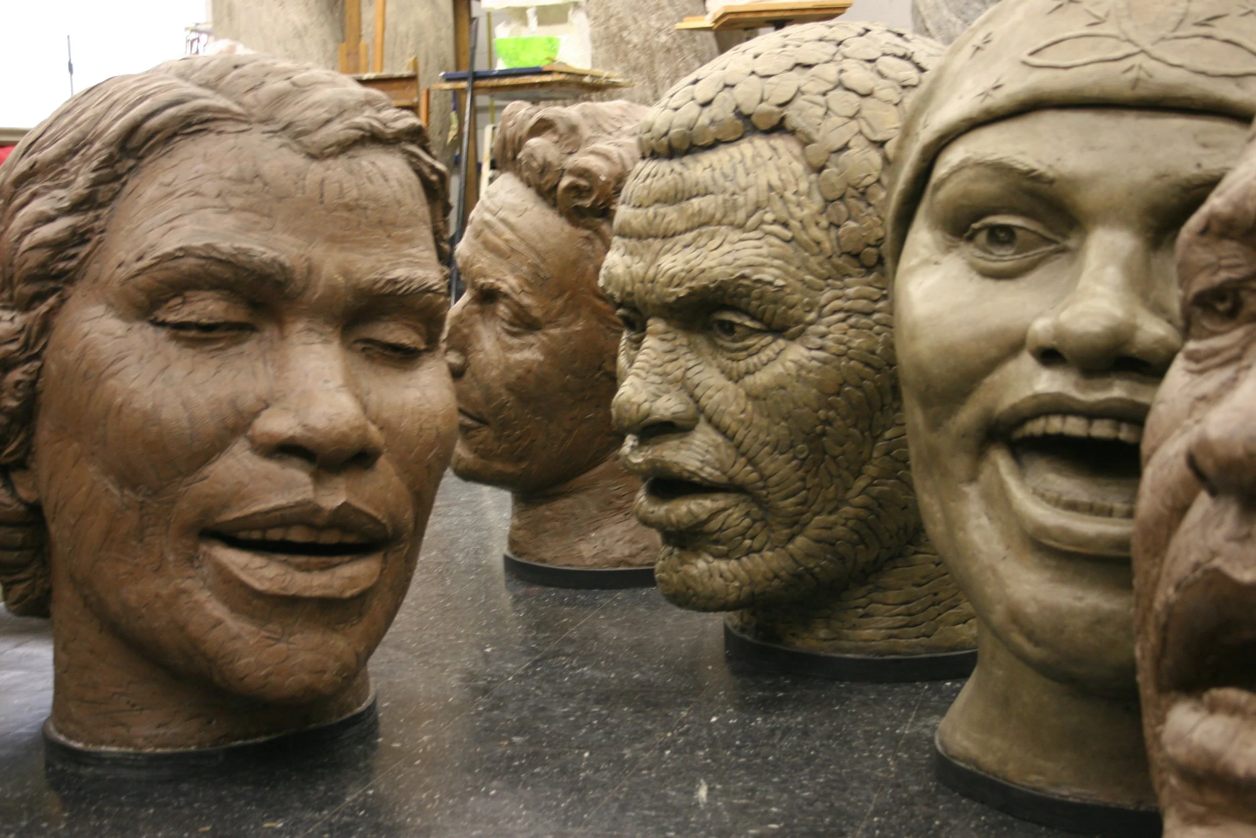 Close-up of detailed plaster sculptures of diverse human faces.  Cultural Heroes