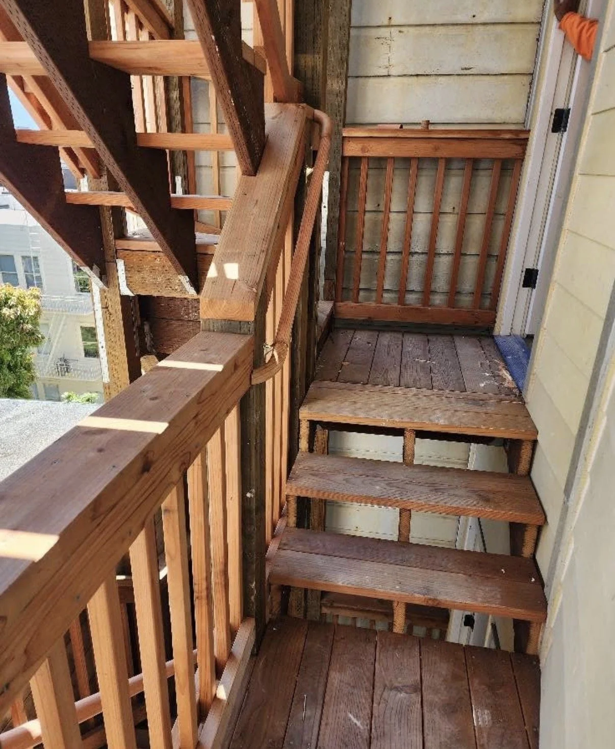 A small outdoor staircase with wooden steps and a wooden railing leads up to a landing. The area appears to be under construction or renovation, with exposed wooden beams and a partially finished wall.