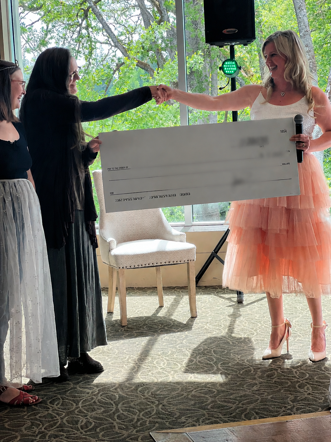 Matched donation check presentation at a nonprofit Princess Tea fundraising event, celebrating funds raised and community support for a local organization.