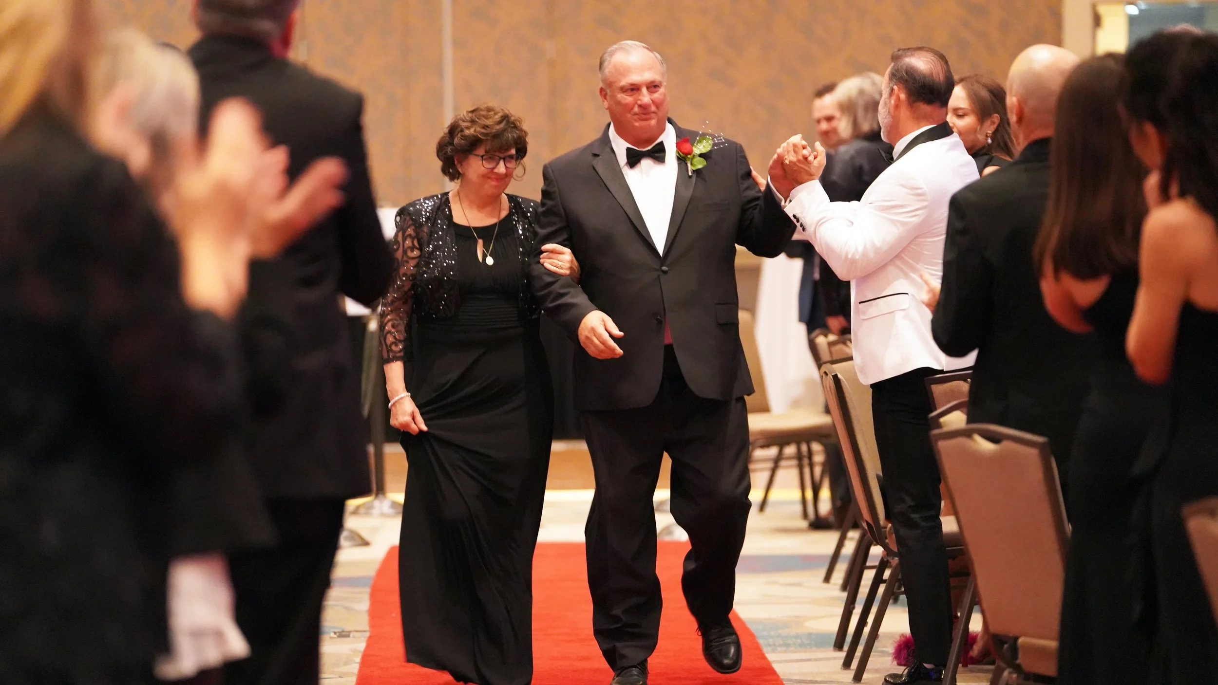 Newly appointed president and his wife exit the red carpet as guests show their appreciation during a Senior Officer Installation event celebrating new leadership.