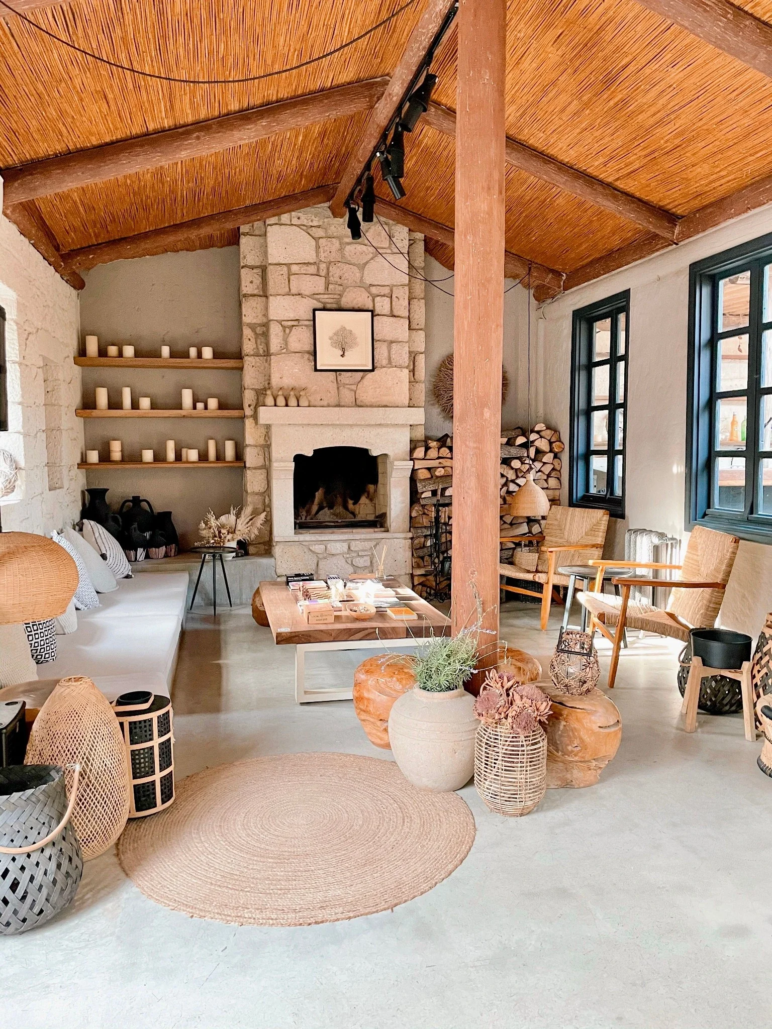 Intérieur d’une maison ancienne rénovée avec cheminée en pierre, poutres en bois et espace de vie ouvert