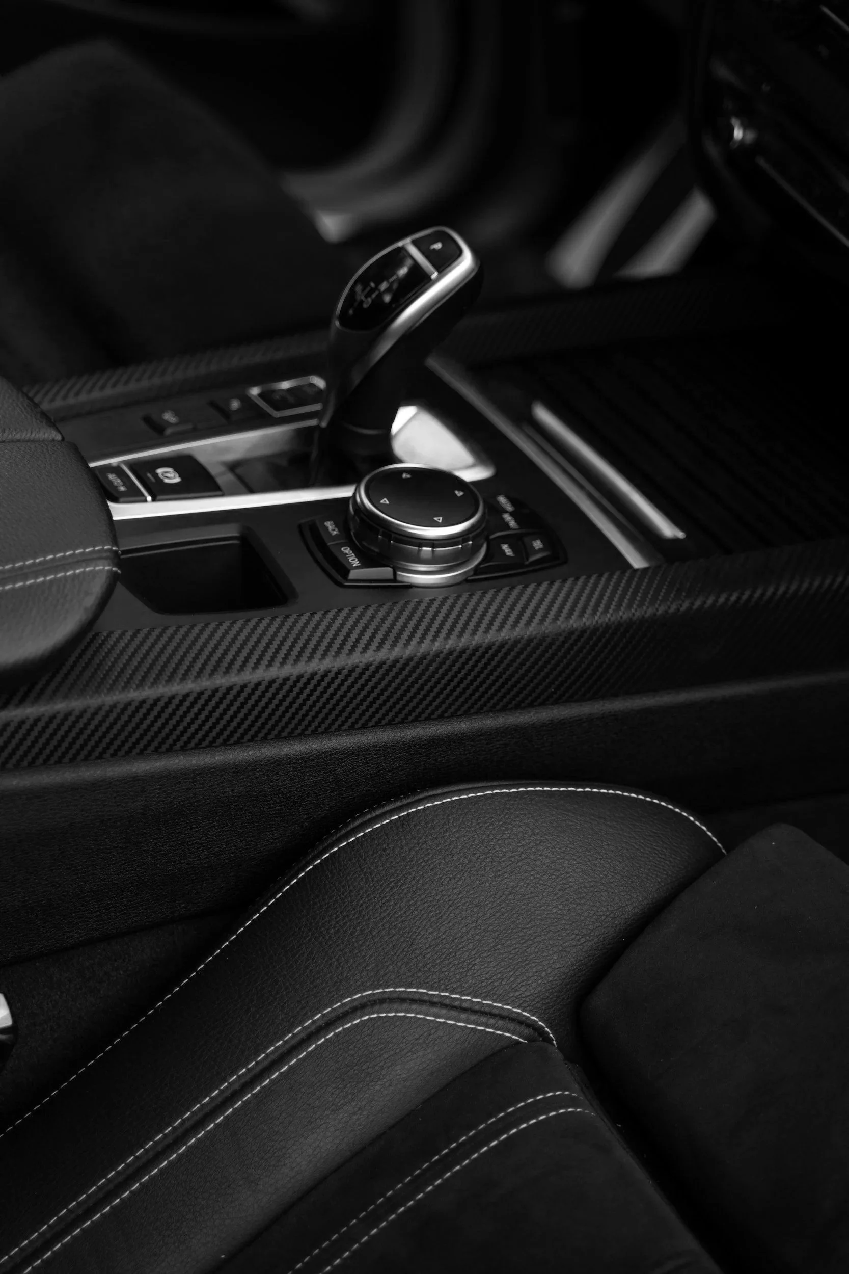 Innenraum eines Autos mit einem Automatikgetriebe, schwarzes Leder mit weißen Nähten, und einem Knauf in der Mittelkonsole.