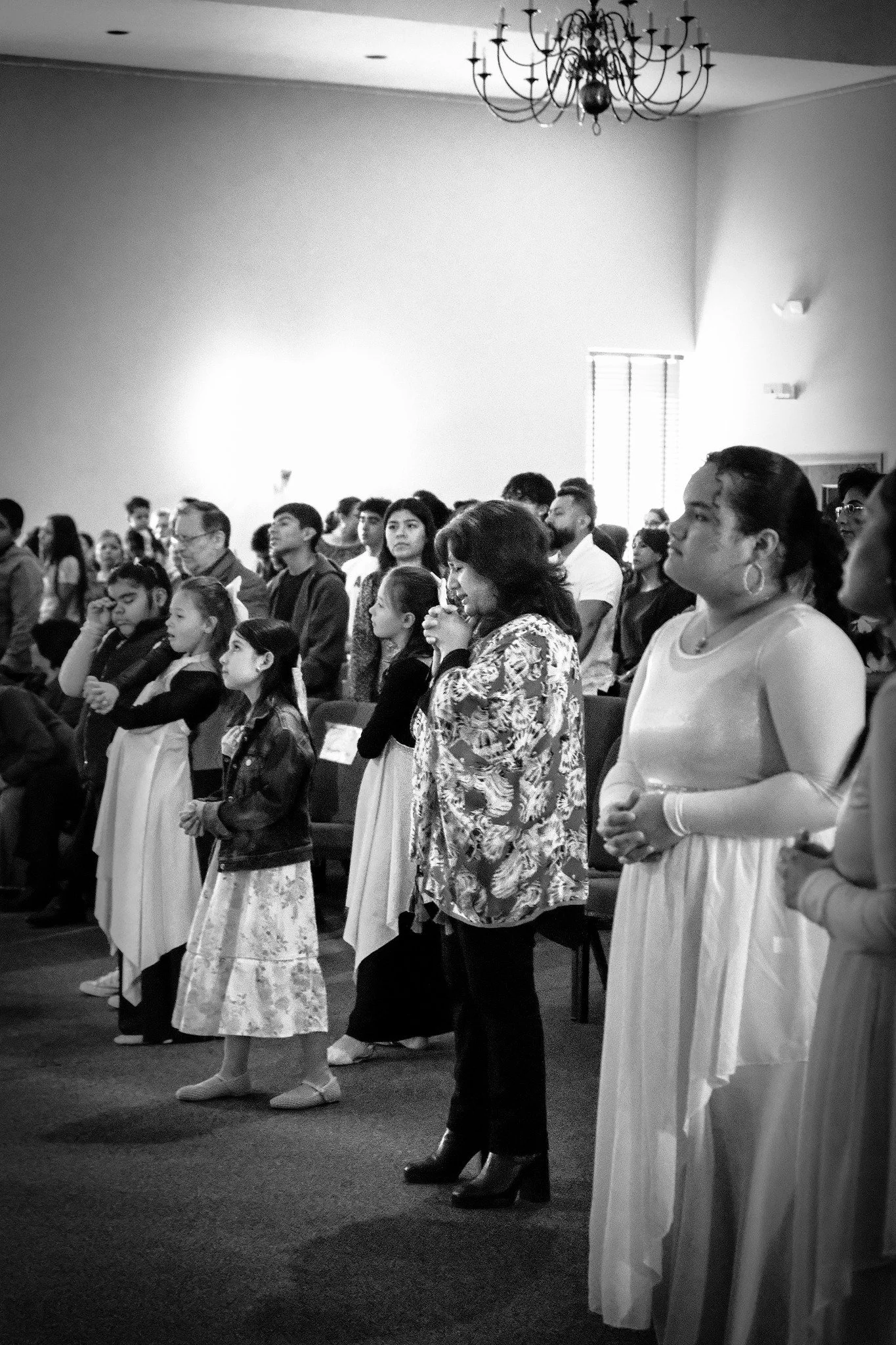 People standing and praying in a church during a service.