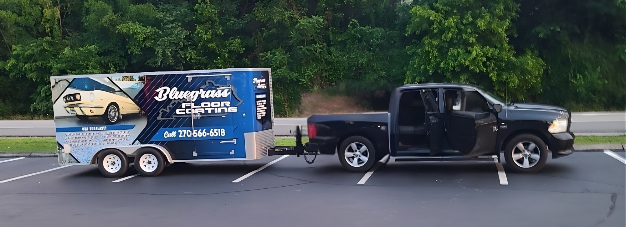 A black pickup truck hauling a trailer advertising Bluegrass Floor Coating parked in a parking lot with trees in the background.