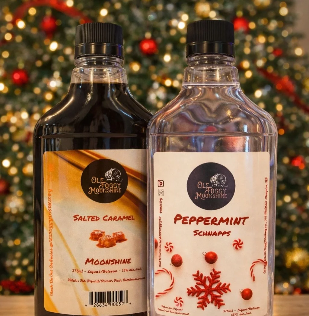 Two bottles of flavored syrup, one labeled Salted Caramel and the other Peppermint Schnapps, with a decorated Christmas tree in the background.