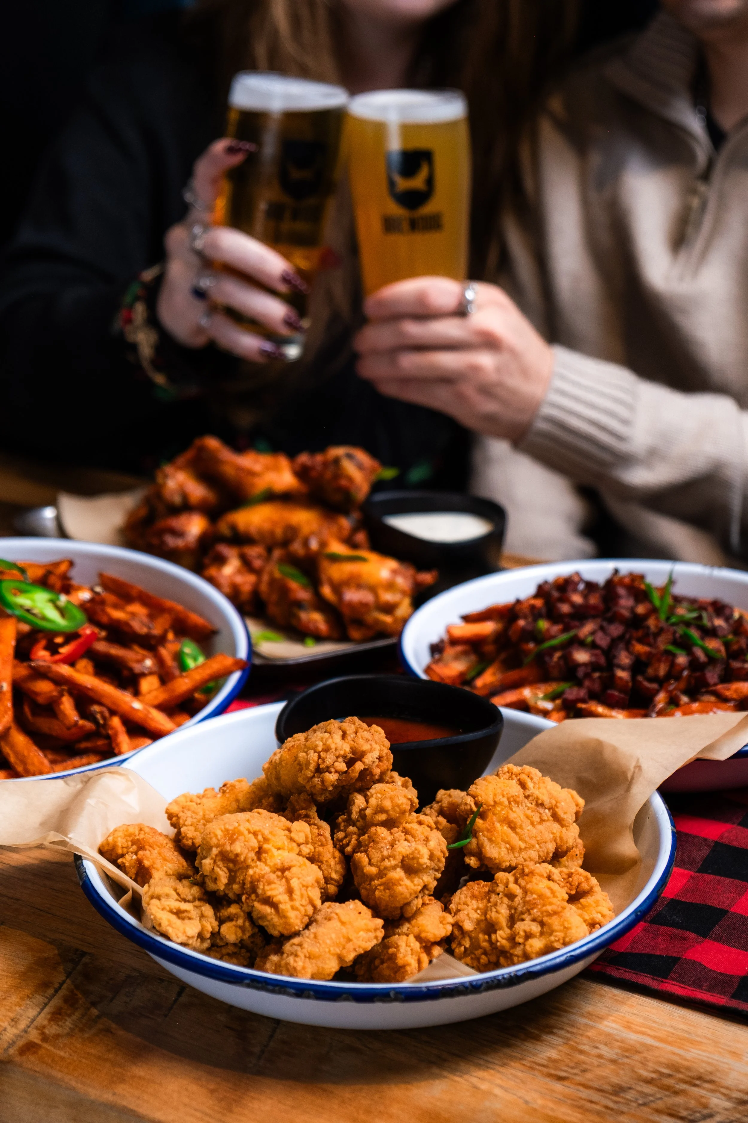 A white bowl filled with fried chicken pieces on parchment paper, placed on a wooden table.