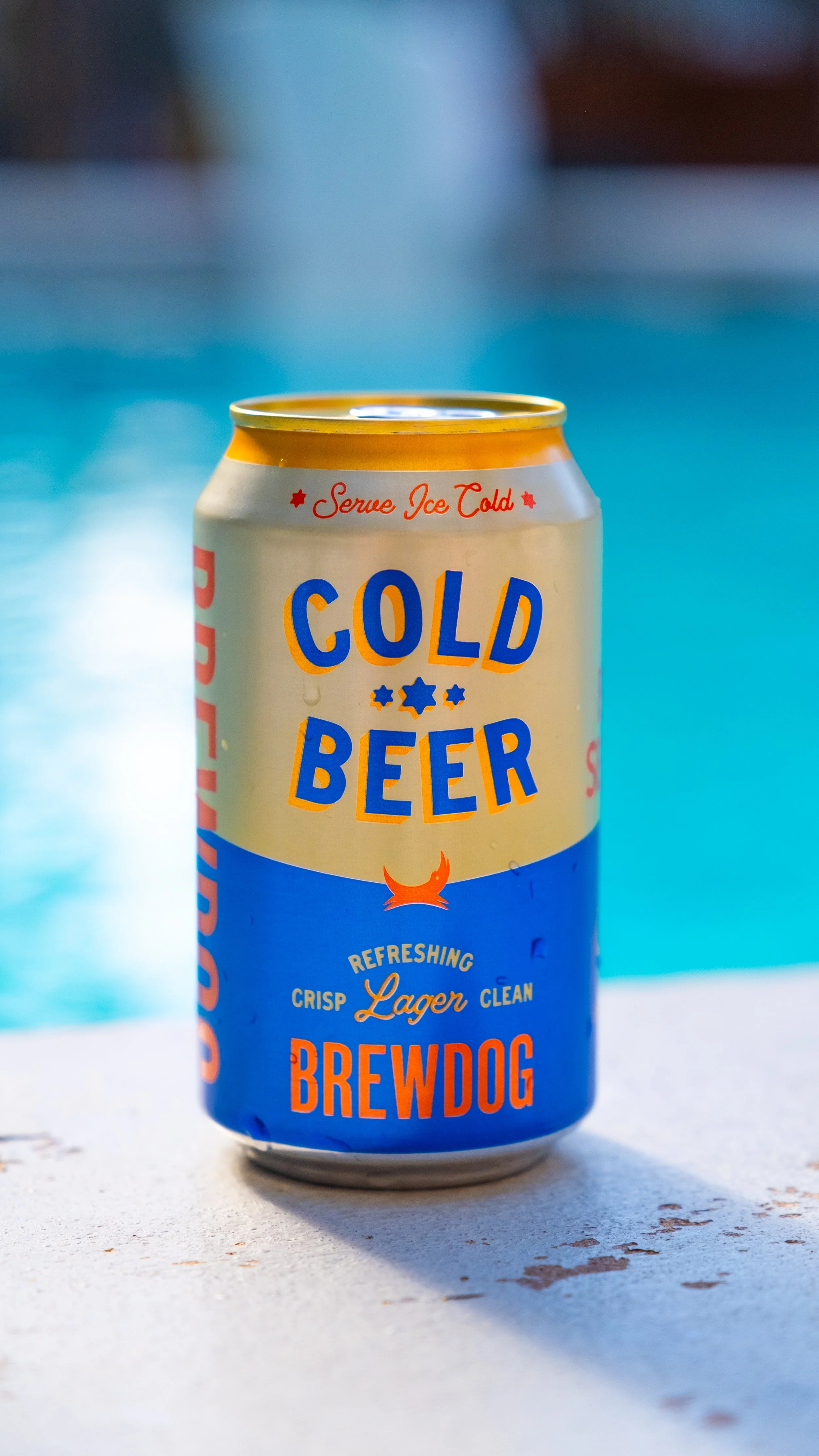 Can of Brewdog Cold Beer on a white surface with a blue background.