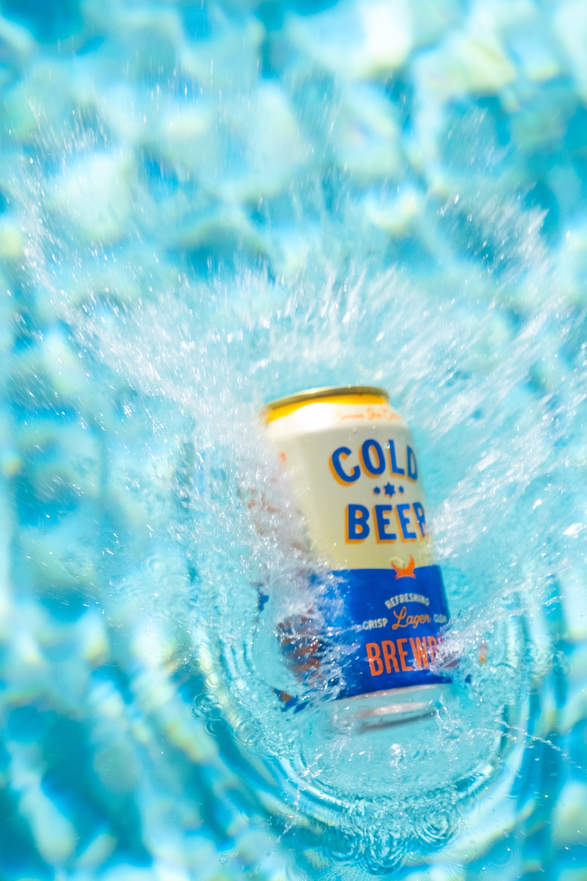 A can of cold beer in water with bubbles and splashes, with the label reading "Cold Beer" and describing it as refreshing lager brew.