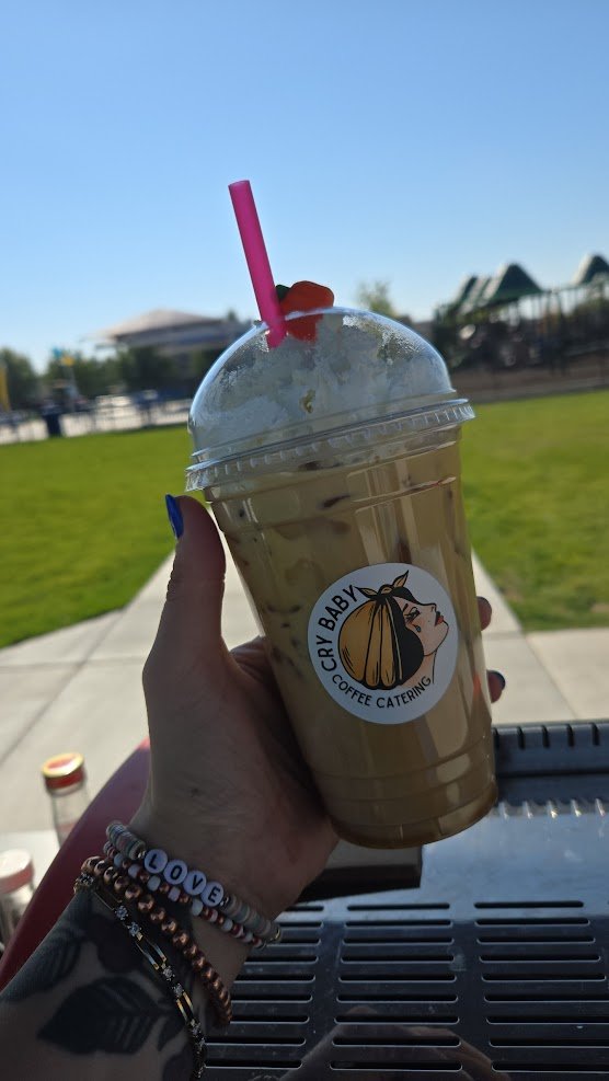 Iced coffee with whipped cream in a Cry Baby Coffee Catering cup at outdoor event in Pavilion Park, Star ID
