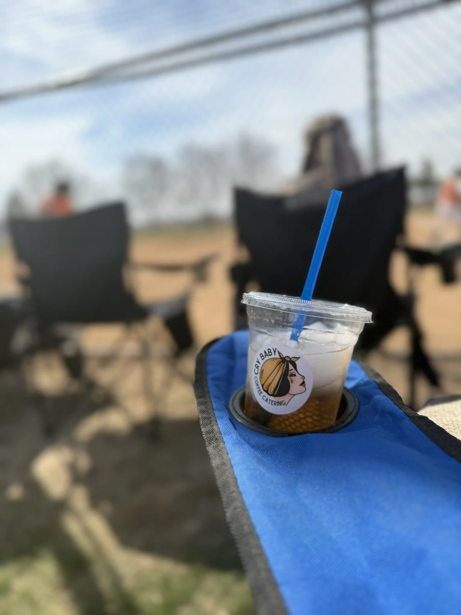 Branded Cry Baby Coffee Catering iced Lotus energy drink in seat cup holder at a sports game.