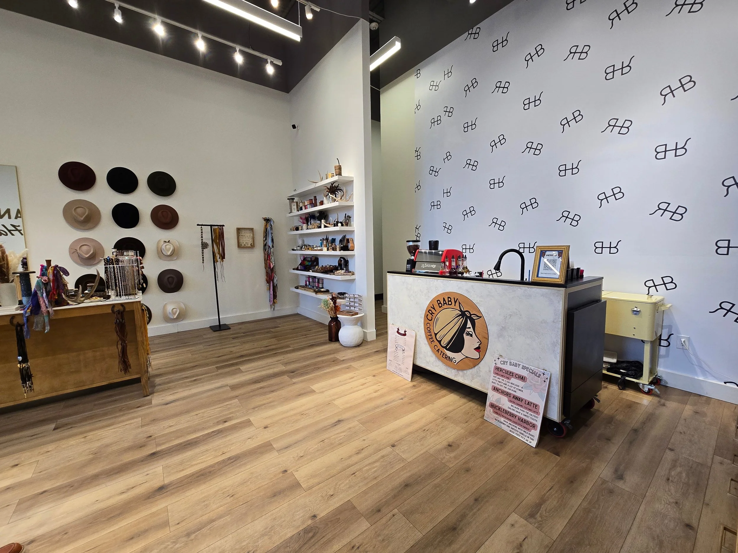 Cry Baby Coffee Catering espresso cart setup inside a boutique retail space with branded cart and menu display.