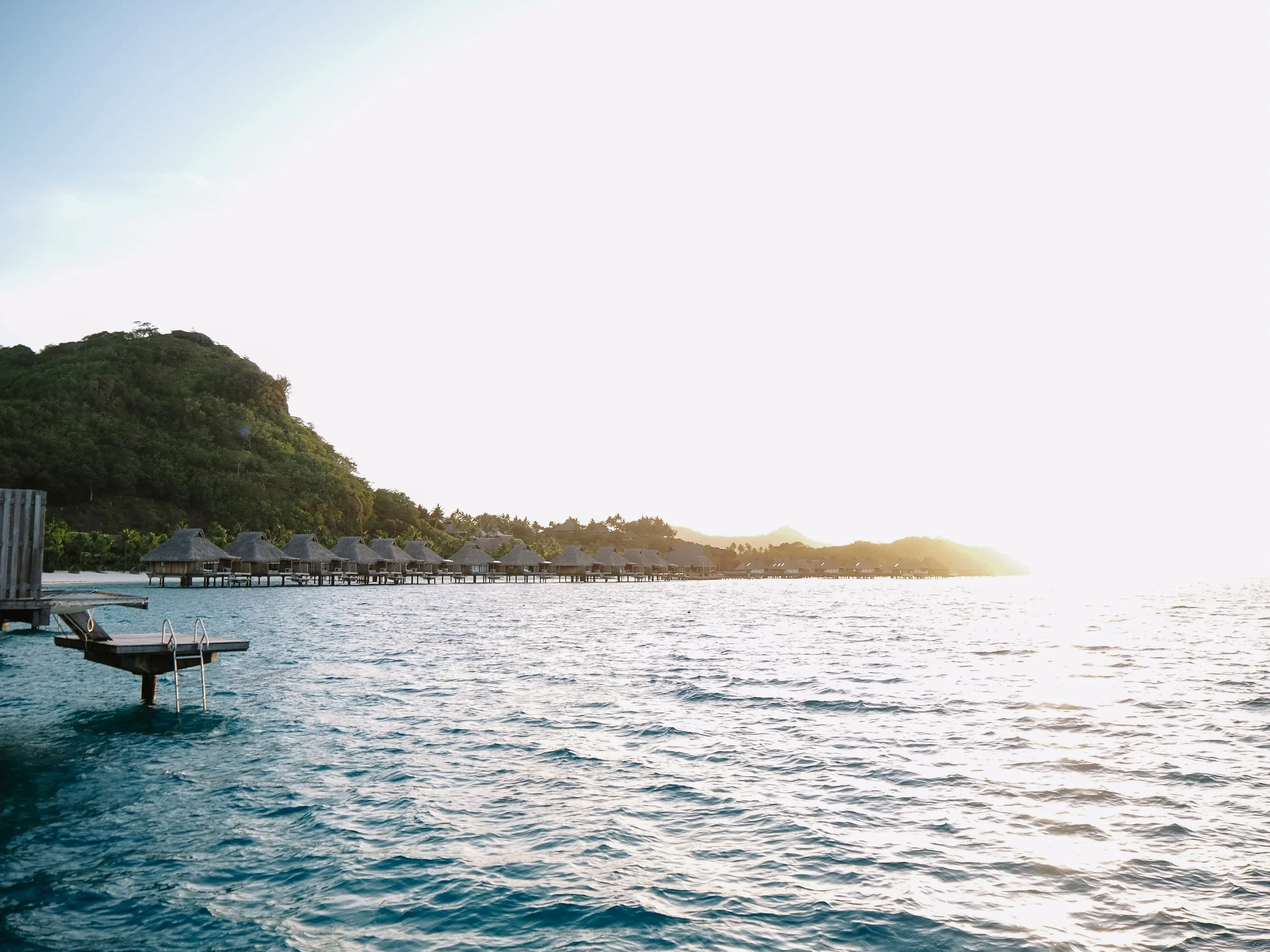 Overwater villas at Conrad Bora Bora Nui set above a turquoise lagoon with mountain views in the background.
