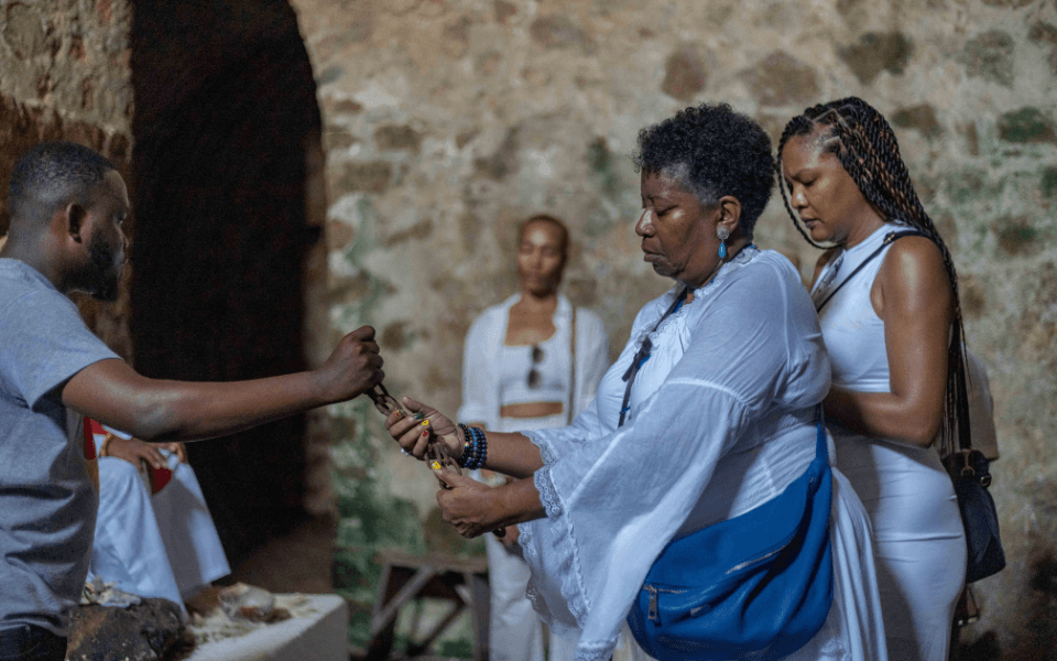 A diasporan woman in a slave dungeon in Ghana holding a shackle