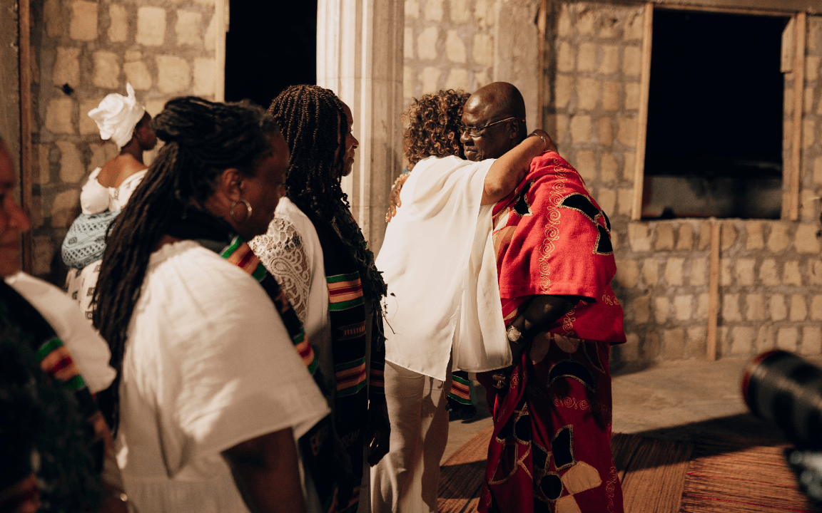 A tour guest hugging a chief with two other guests at a naming ceremony in Ghana