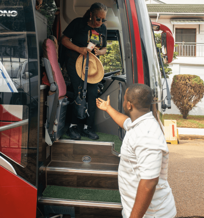 A local guide in Ghana with his hand stretched to help a guest get down a bus 
