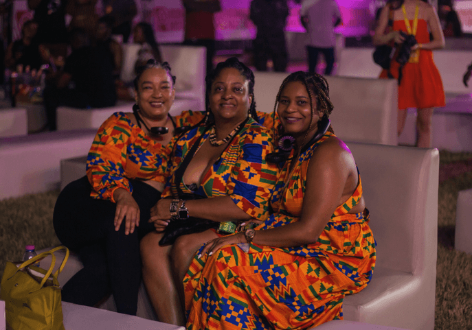 3 ladies dressed in African wear, kente