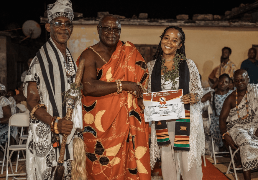 A diasporan traveler receiving a naming ceremony certificate in Ghana during a tour