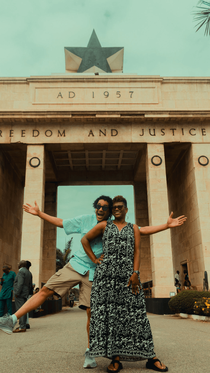 A couple happily posing for a photo in front of the popular Black Star Square monument in Ghana