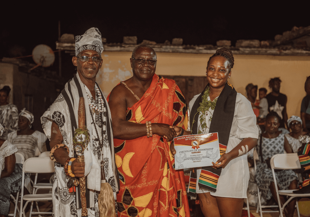Two chiefs in presenting a naming ceremony certificate to a diasporan traveler