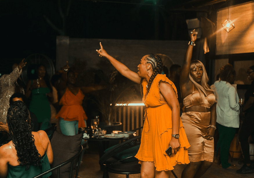 A group of travelers dancing at a bar in Ghana with hands in the air for Nightlife experience in Ghana