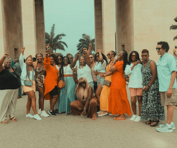 A Group of tour guests chappily taking a group photo in front of The Black Star Square Monument
