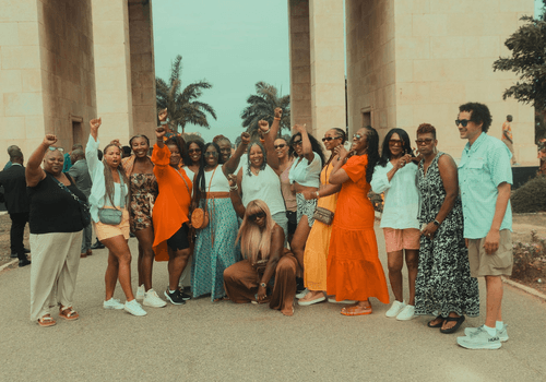 A group of diasporan travelers at the black star gate in Ghana posing for a picture