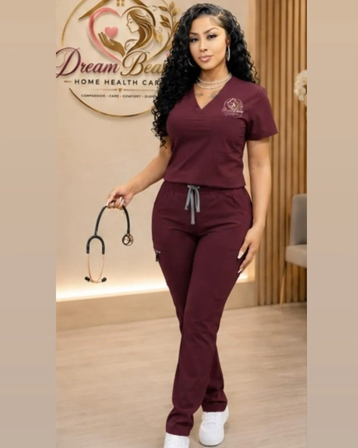 A woman in burgundy scrubs holding a stethoscope, standing in a medical office with a sign that reads 'Dream Beauty Home Health Care' behind her.