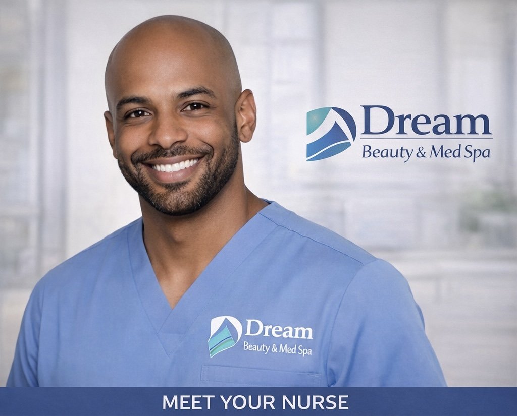 A smiling male nurse wearing blue scrubs with the logo of Dream Beauty & Med Spa, standing in front of a light-colored, blurred background, with a corporate logo for Dream Beauty & Med Spa behind him.