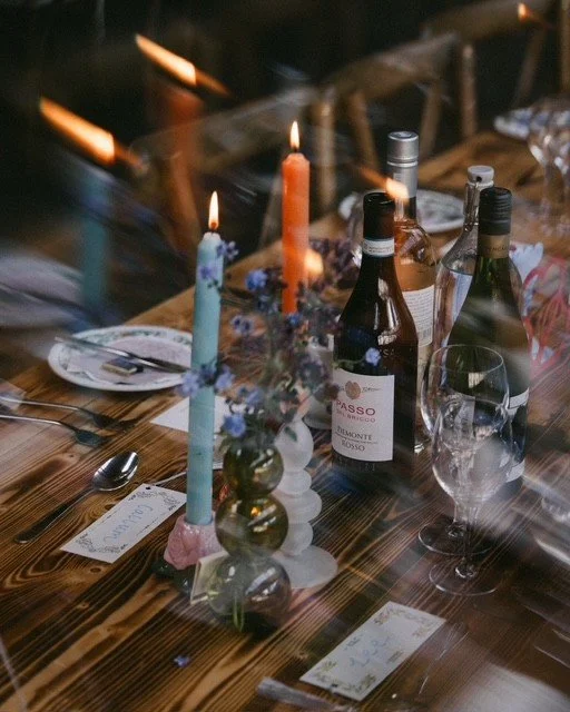 Dinner table set with candles, wine bottles, glasses, and place cards.